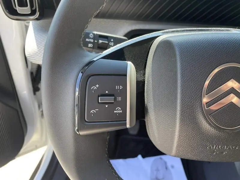 Gros plan sur le volant noir du Citroën C3 Nouvelle 2025 blanc, avec commandes de régulateur de vitesse visibles à gauche.