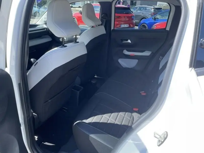 Intérieur arrière de la Citroën C3 Nouvelle blanche 2025, vue côté droit avec sièges noirs et blancs et porte ouverte.