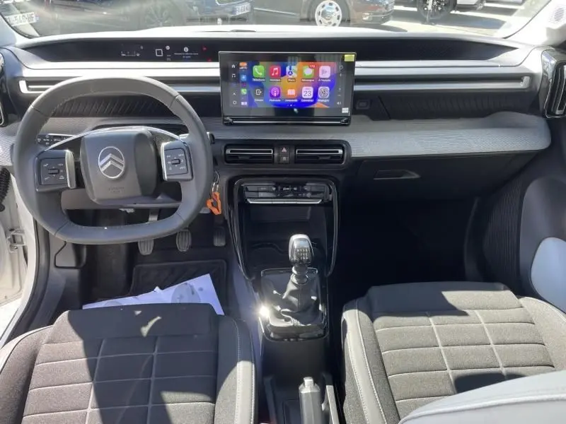 Intérieur de la Citroën C3 Nouvelle 2025 vue de face, tableau de bord moderne avec écran tactile et boîte manuelle noire.