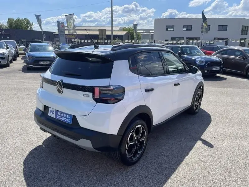 Vue 3/4 arrière droite d'une Citroën C3 Nouvelle blanche 2025 avec toit noir et jantes distinctives en concession.
