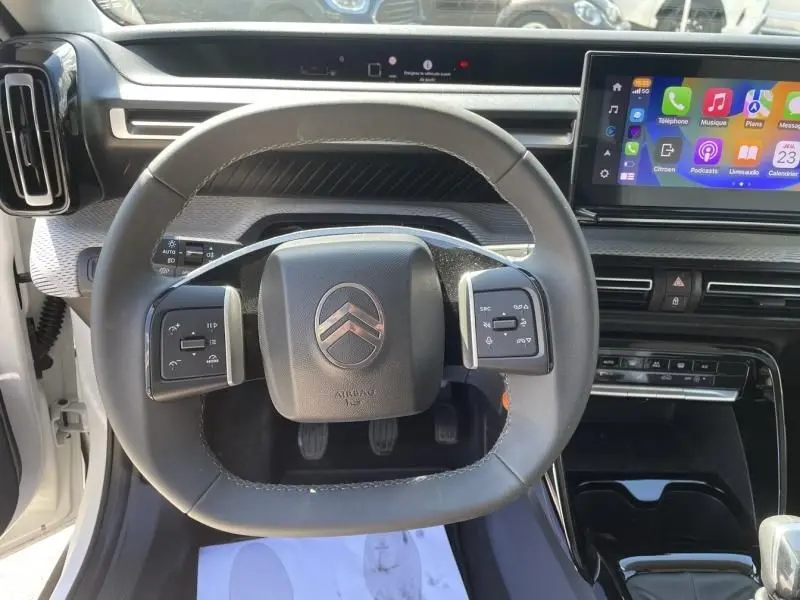 Vue rapprochée du volant noir de la Citroën C3 Nouvelle 2025 blanche, avec tableau de bord numérique et écran tactile coloré.