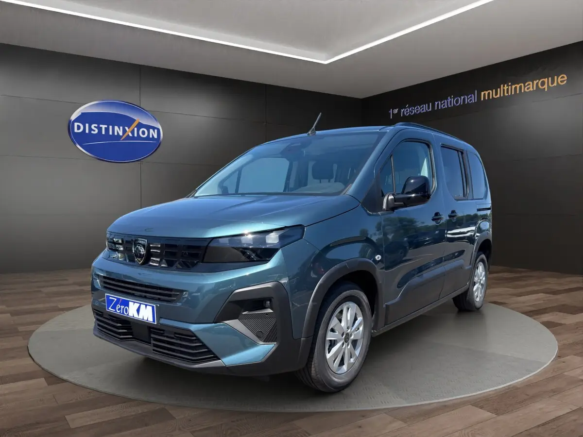 Peugeot Rifter bleu en vue 3/4 avant droit, avec calandre noire et jantes argentées, en showroom intérieur.