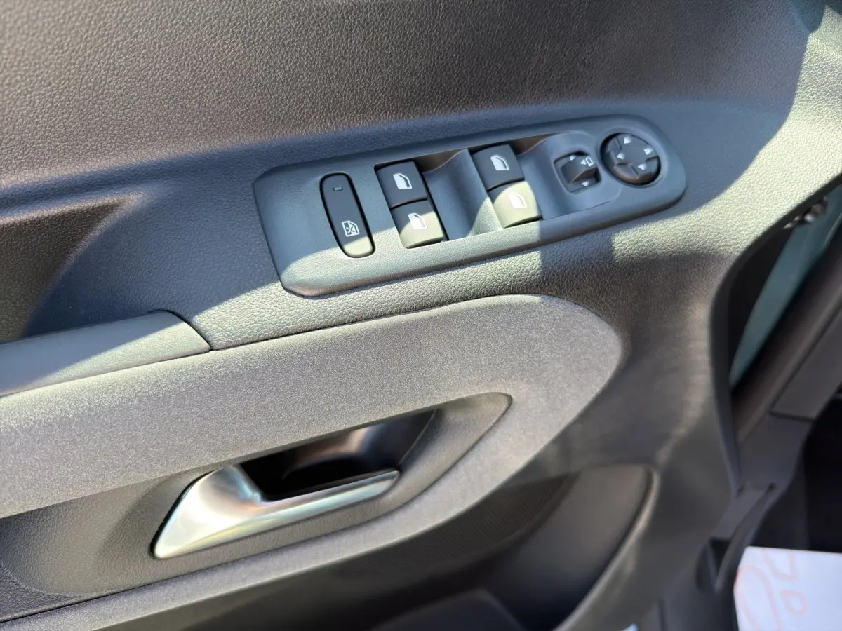 Détail de la porte côté conducteur du Peugeot Rifter bleu 2026 avec commandes électriques des vitres et rétroviseurs.