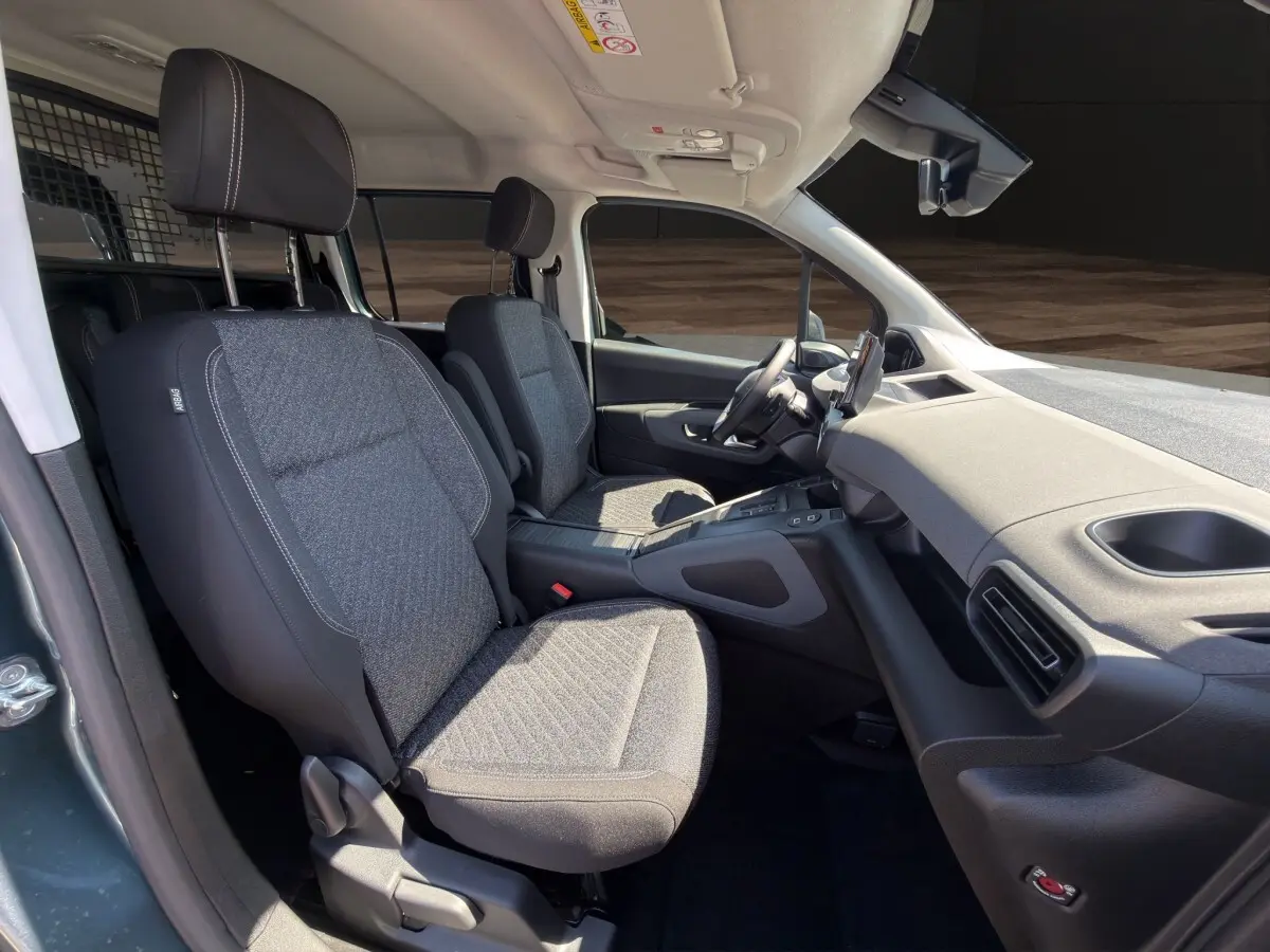 Vue intérieure côté droit du Peugeot Rifter 2026, sièges tissu gris et tableau de bord moderne avec écran tactile.