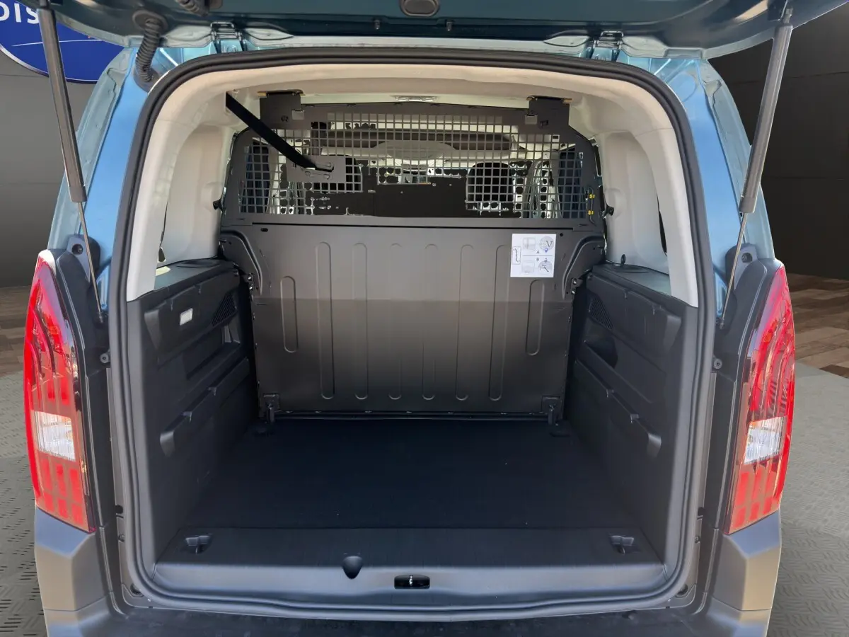 Vue arrière du coffre ouvert du Peugeot Rifter bleu, montrant la cloison de séparation métallique et l'espace de chargement vide.