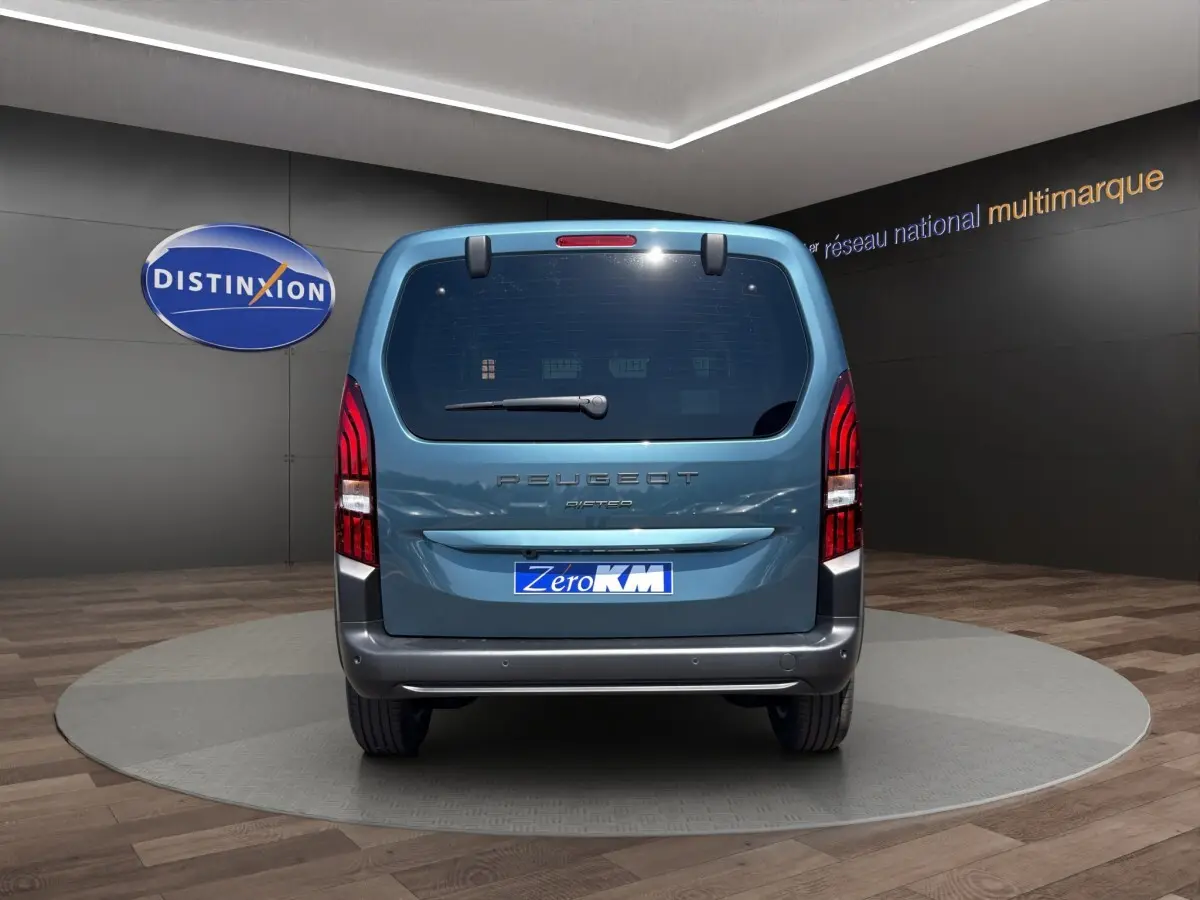 Vue arrière d'un Peugeot Rifter bleu 2026 dans un showroom avec logo Distinxion en arrière-plan.