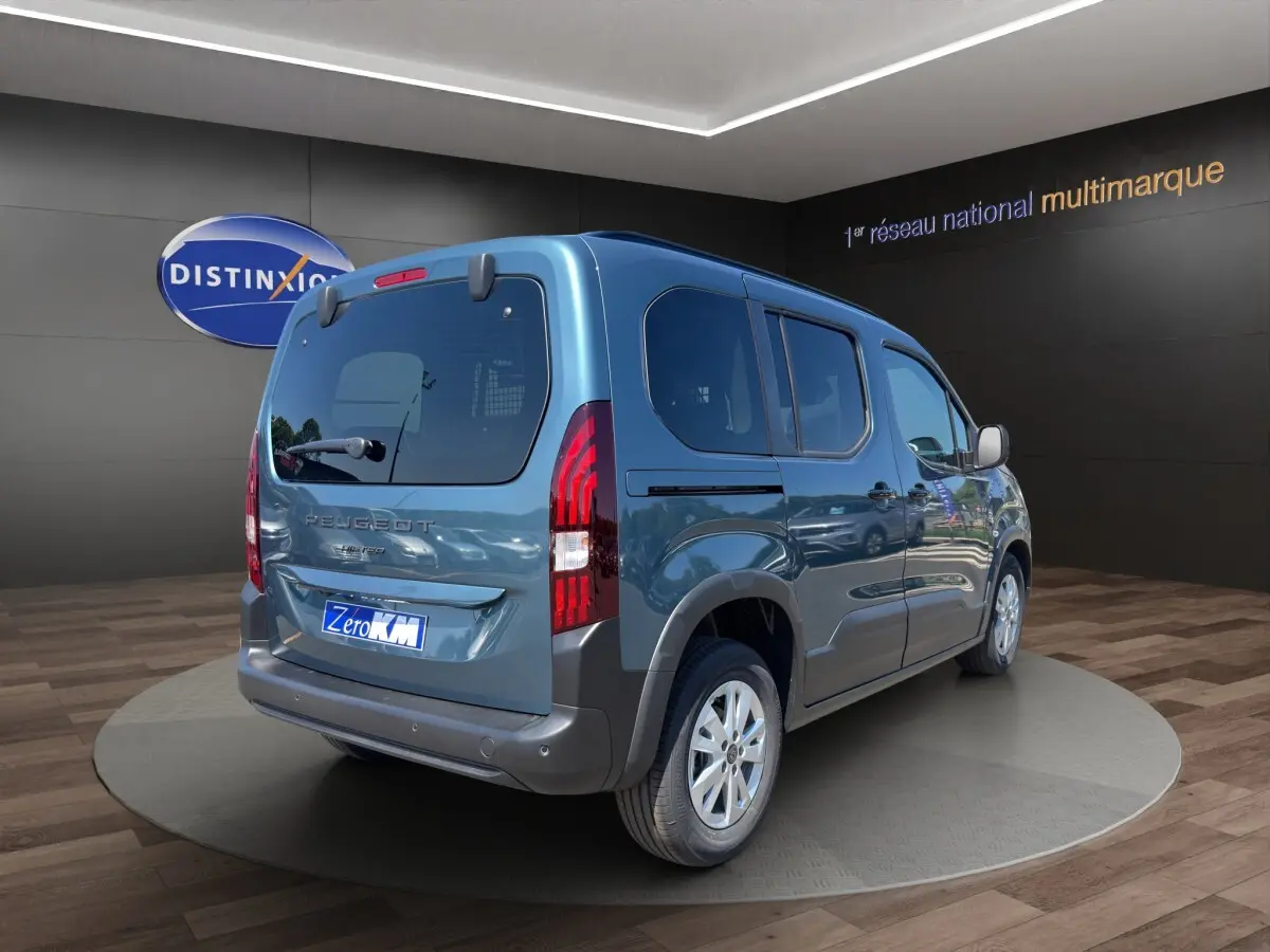 Peugeot Rifter bleu vue 3/4 arrière droit en intérieur, avec feux arrière verticaux et jantes argentées.