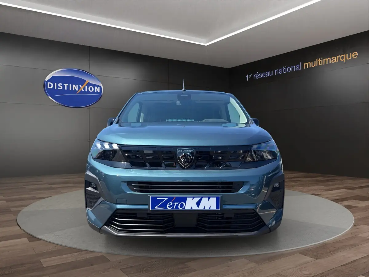 Vue frontale du Peugeot Rifter bleu 2026 avec calandre noire et logo lion distinctif, en showroom.