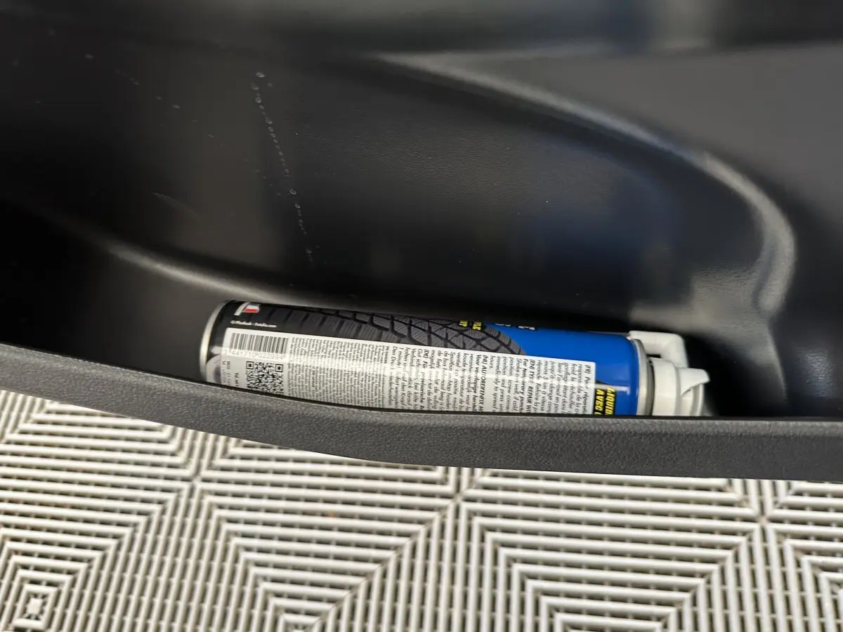 Gros plan sur le rangement de porte côté gauche d'une Aixam Ambition 0.5 City Pack bleu avec bombe anti-crevaison.