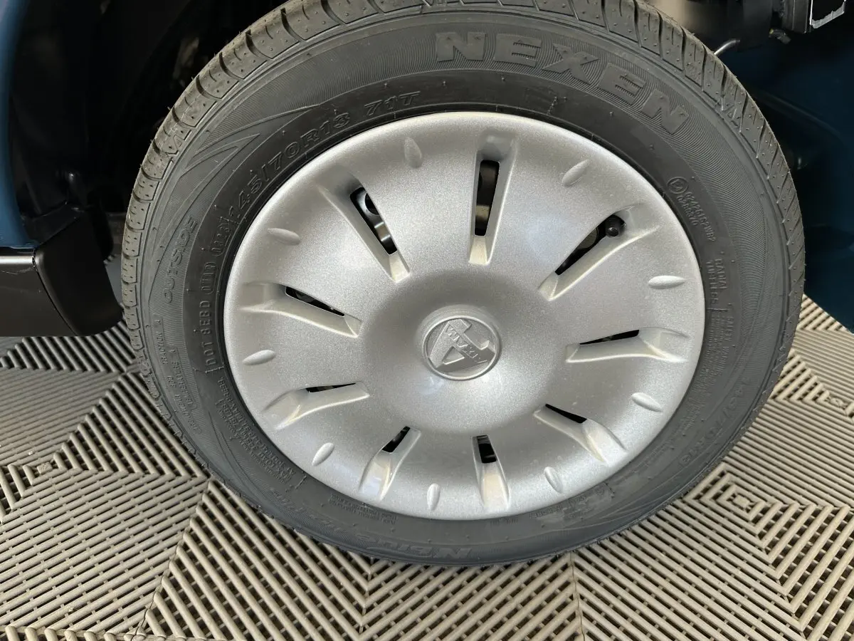 Gros plan sur la roue avant droite de l'AIXAM AMBITION 0.5 CITY PACK bleu avec enjoliveur argenté et logo central.