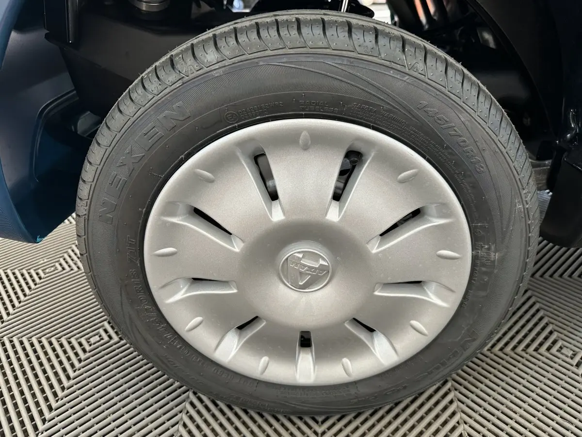 Gros plan sur la roue avant droite d'une Aixam Ambition 0.5 City Pack bleu avec jante argentée et logo central.