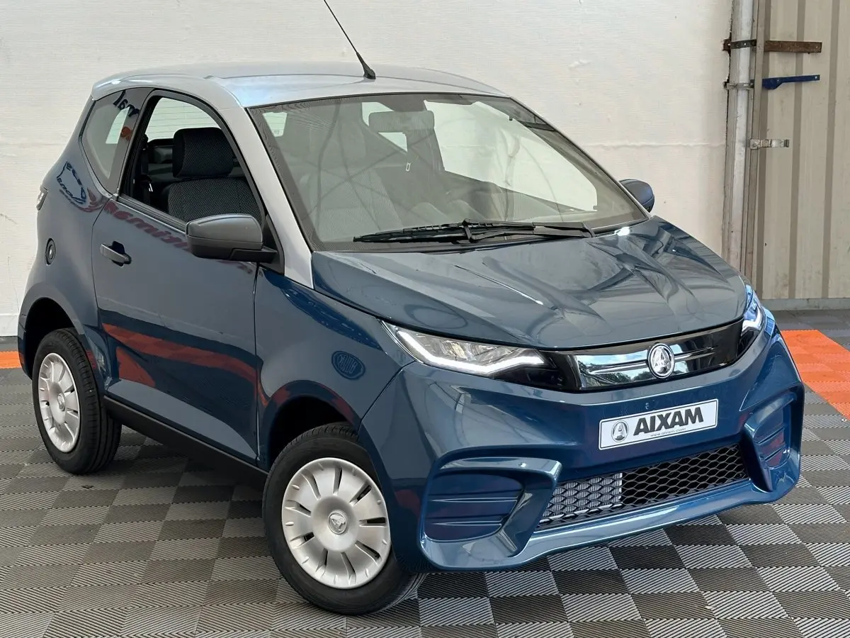 Vue 3/4 avant d'une Aixam Ambition 0.5 City Pack bleu avec rétroviseur caméra côté gauche et jantes argentées.