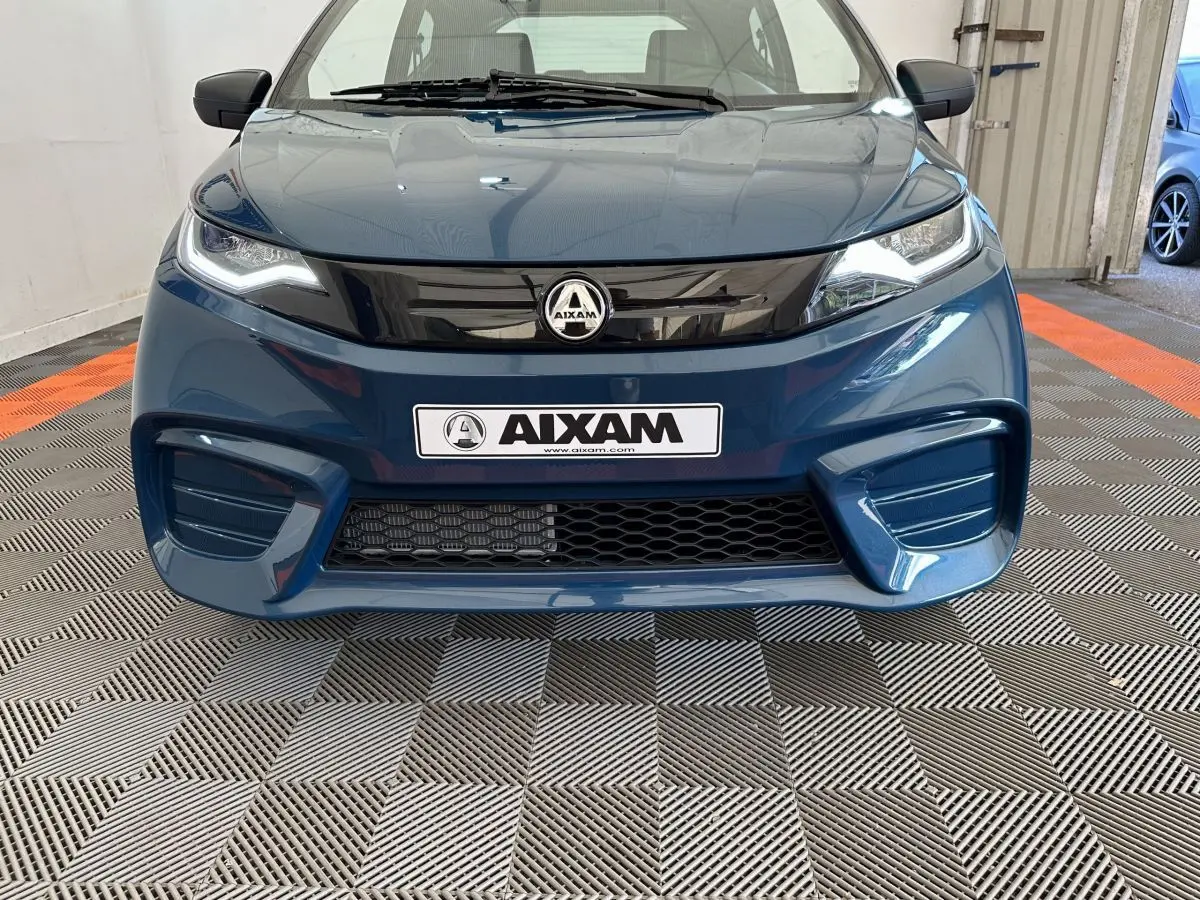 Vue frontale d'une Aixam Ambition 0.5 City Pack bleu 2025 avec calandre noire brillante et logo central visible.