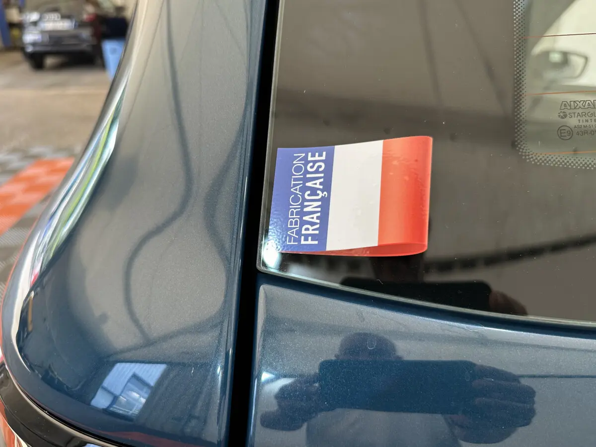 Gros plan sur la partie arrière gauche bleu métallisé d'une Aixam Ambition 0.5 City Pack avec autocollant "Fabrication Française" visible.