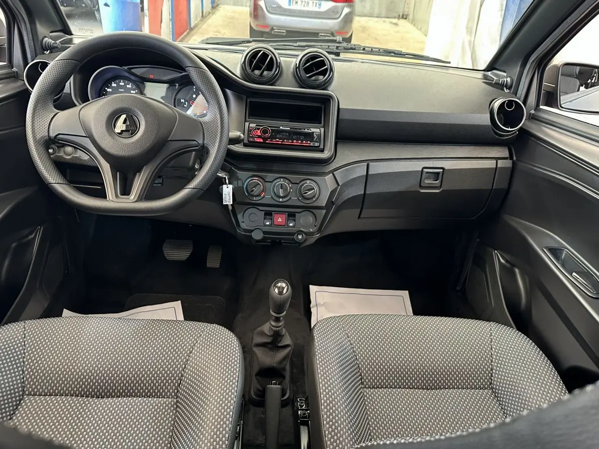 Vue intérieure avant de l'AIXAM AMBITION 0.5 CITY PACK 2025 avec tableau de bord noir et volant à trois branches.