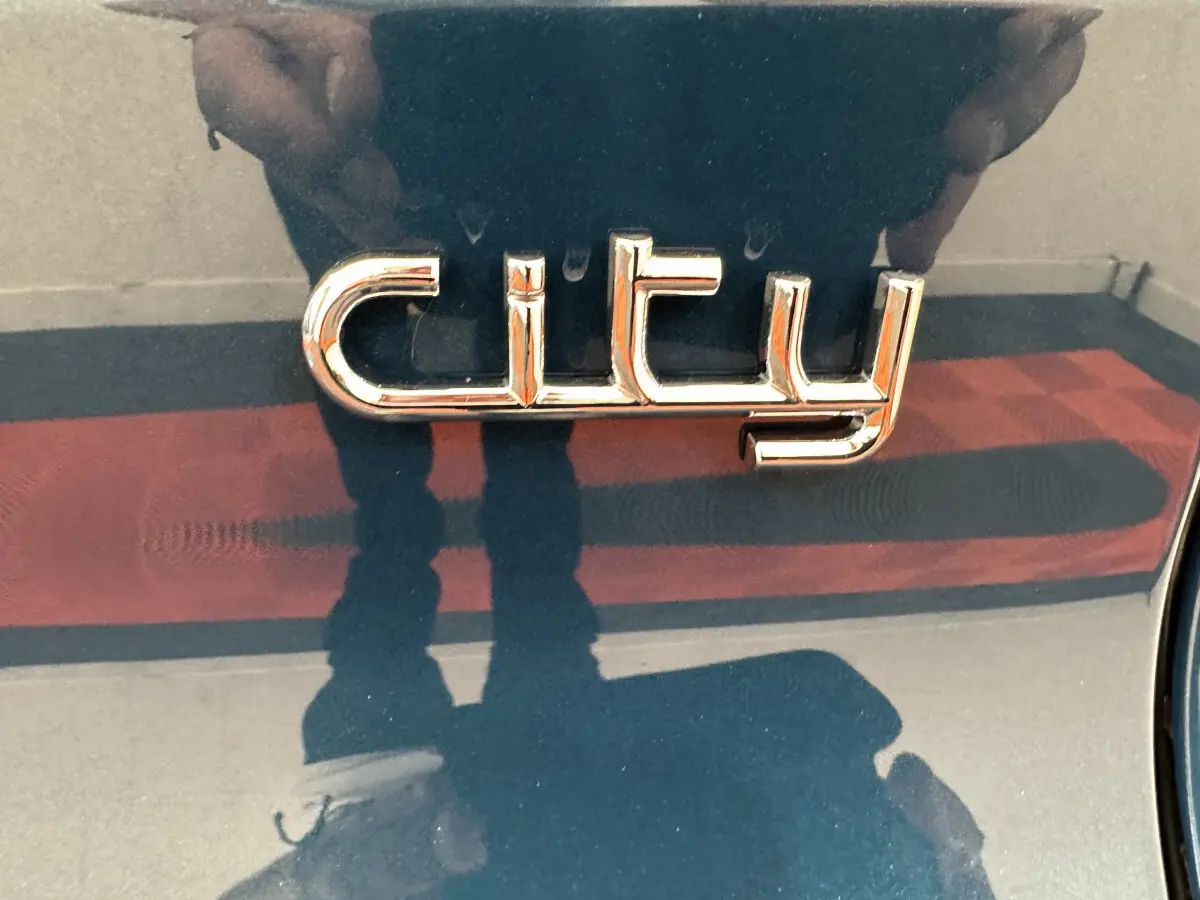 Gros plan sur l’inscription chrome "city" sur la carrosserie bleue de l’AIXAM AMBITION 0.5 CITY PACK 2025.