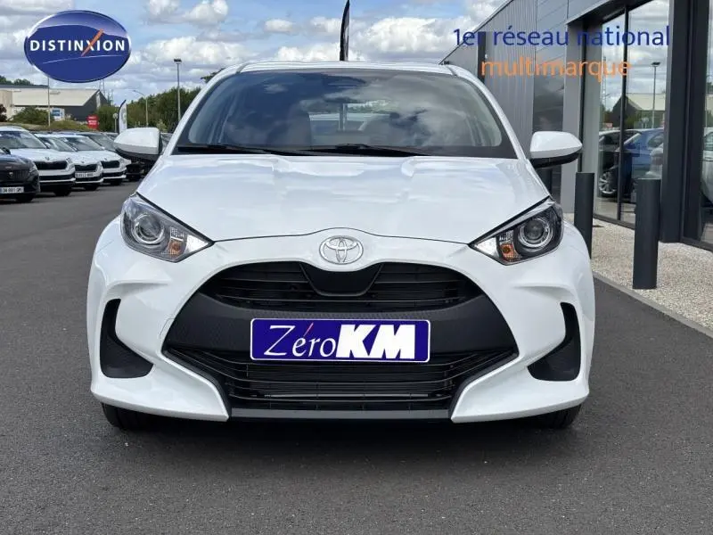 Vue frontale d'une Toyota Yaris 116h Dynamic blanche 2025 avec calandre noire et plaque Zero KM visible