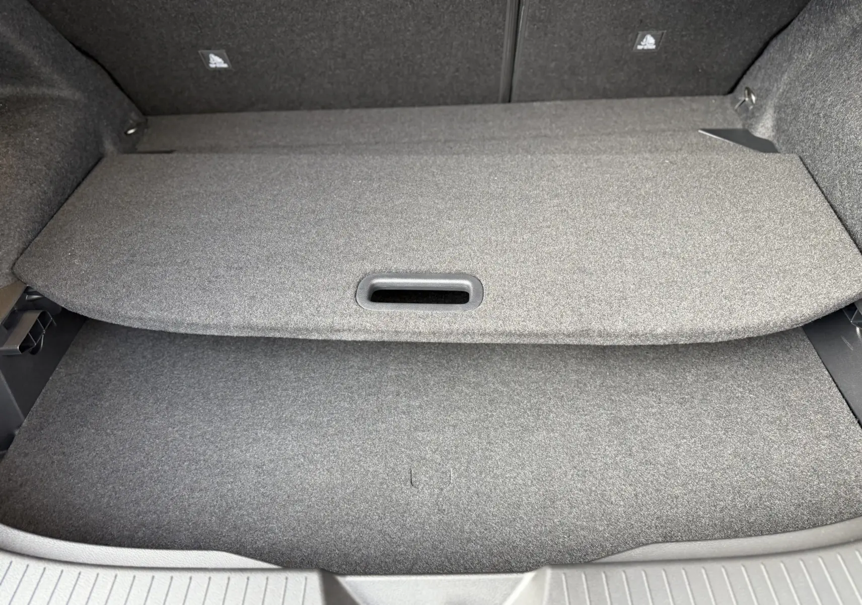 Vue intérieure du coffre du Nissan Qashqai 1.5 E-POWER 2025, avec cache-bagages gris et revêtement tissu.