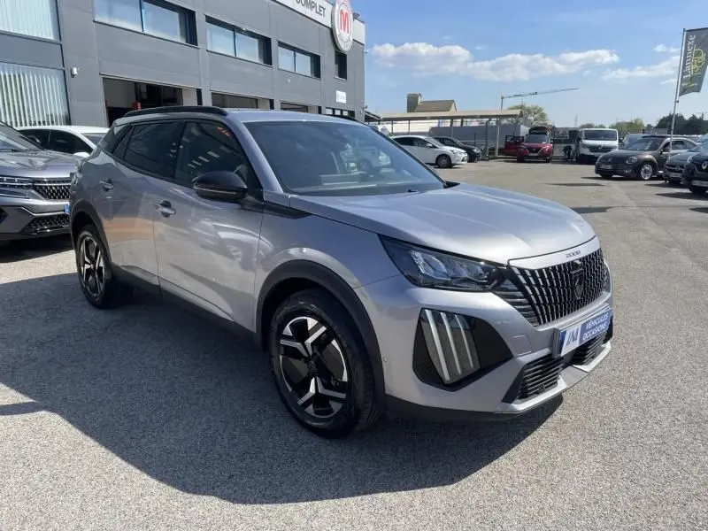 Peugeot 2008 gris métal vue 3/4 avant droit, avec calandre noire distinctive et jantes au design moderne.