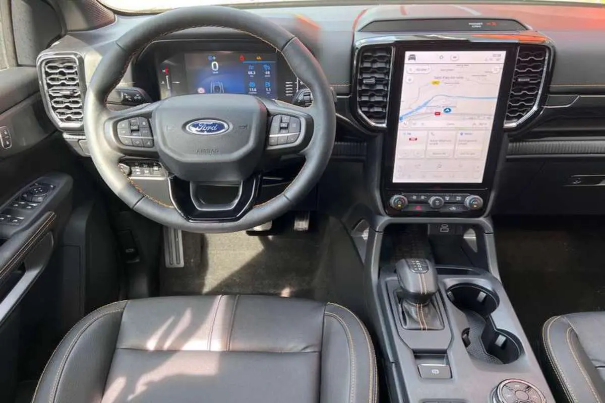 Vue intérieure frontale du Ford Ranger 2026, volant cuir multifonctions, écran tactile vertical et sellerie noire avec surpiqûres.