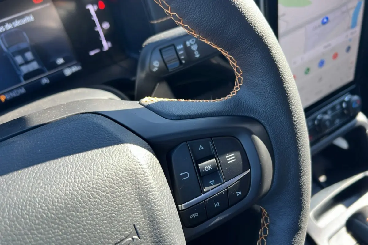Gros plan sur le volant cuir noir avec surpiqûres marron et commandes multifonctions du Ford Ranger 2026.