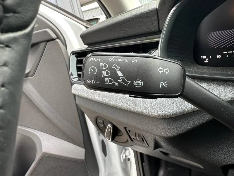 Gros plan sur la commande multifonction noire à gauche du volant dans l’habitacle blanc cristal du Skoda Scala 2025.