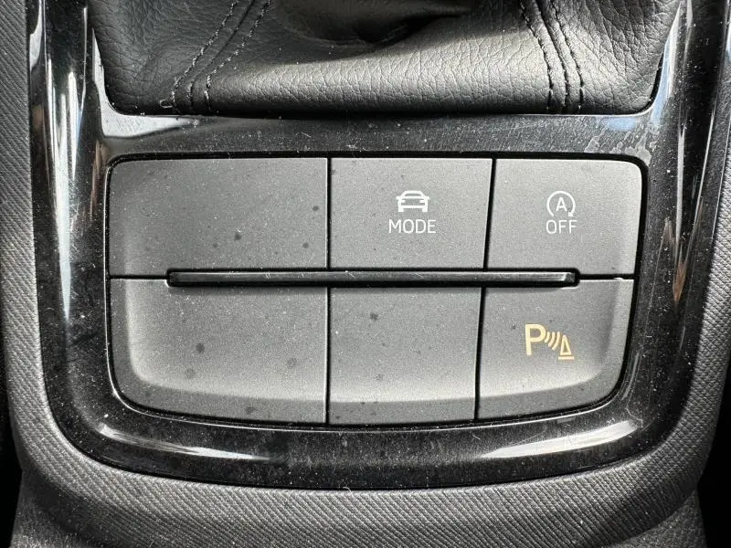Gros plan sur les boutons de commande du mode de conduite et du stationnement du Skoda Scala blanc cristal, intérieur noir.