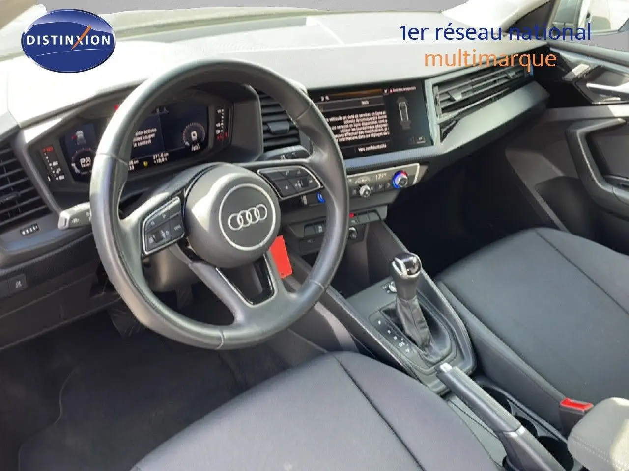 Vue intérieure de l'Audi A1 Sportback 2023, tableau de bord et volant cuir noir avec console centrale et boîte auto.