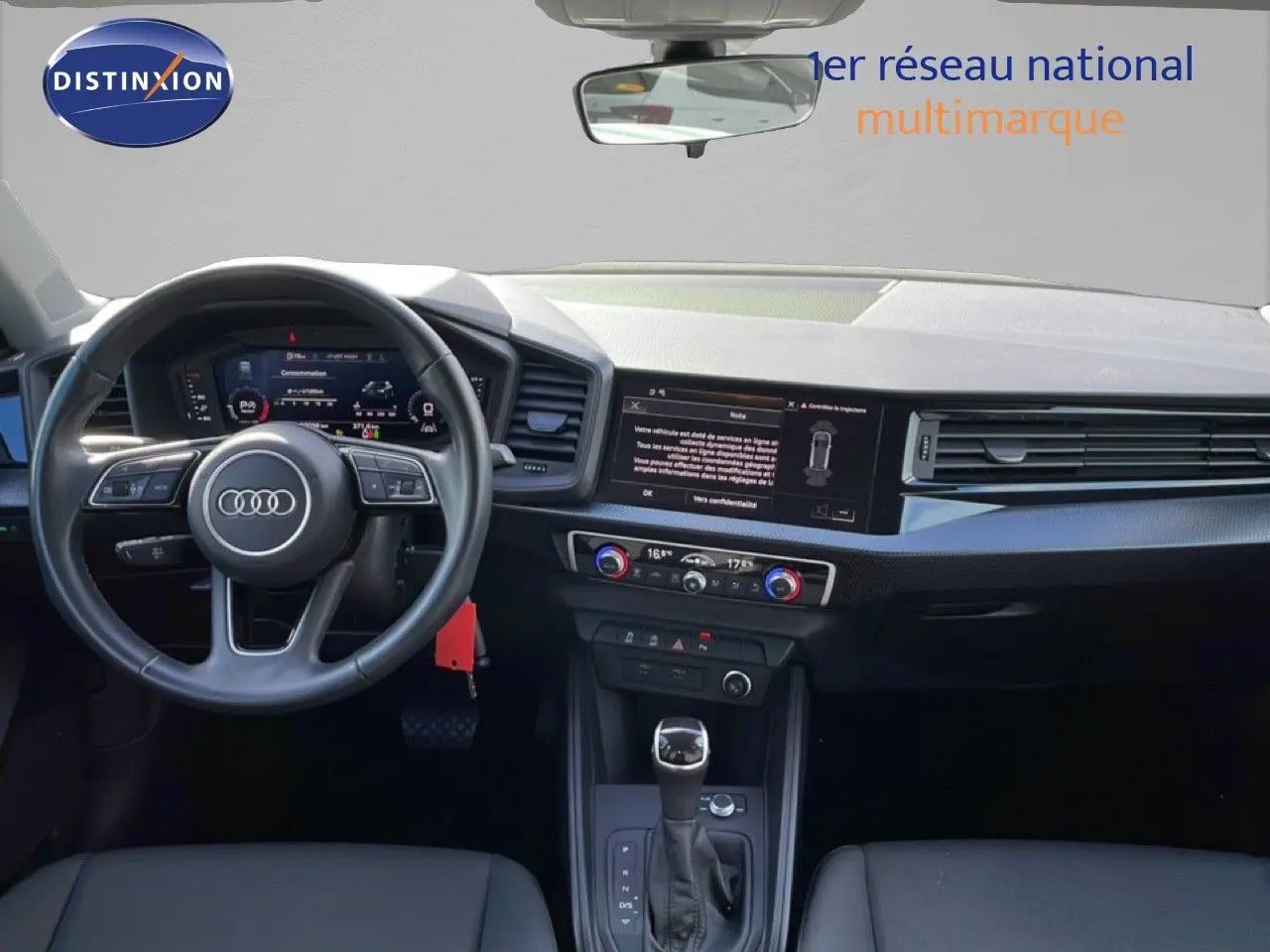Intérieur Audi A1 Sportback 2023 vu de face, tableau de bord noir avec écran tactile et volant cuir multifonction.