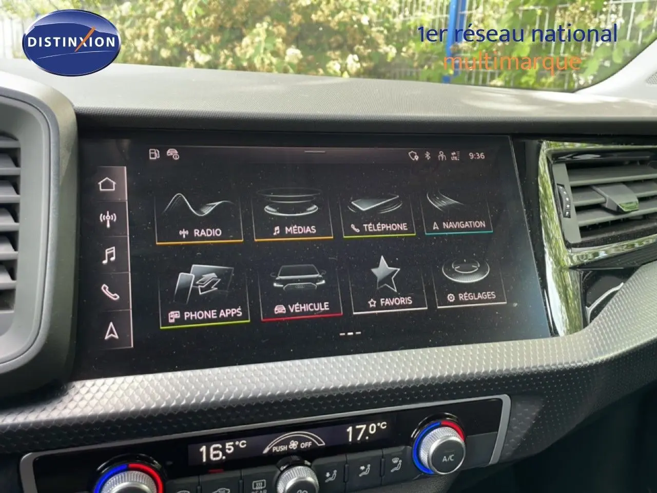 Gros plan sur l'écran tactile central et la console de climatisation d'une Audi A1 Sportback noire, intérieur moderne.