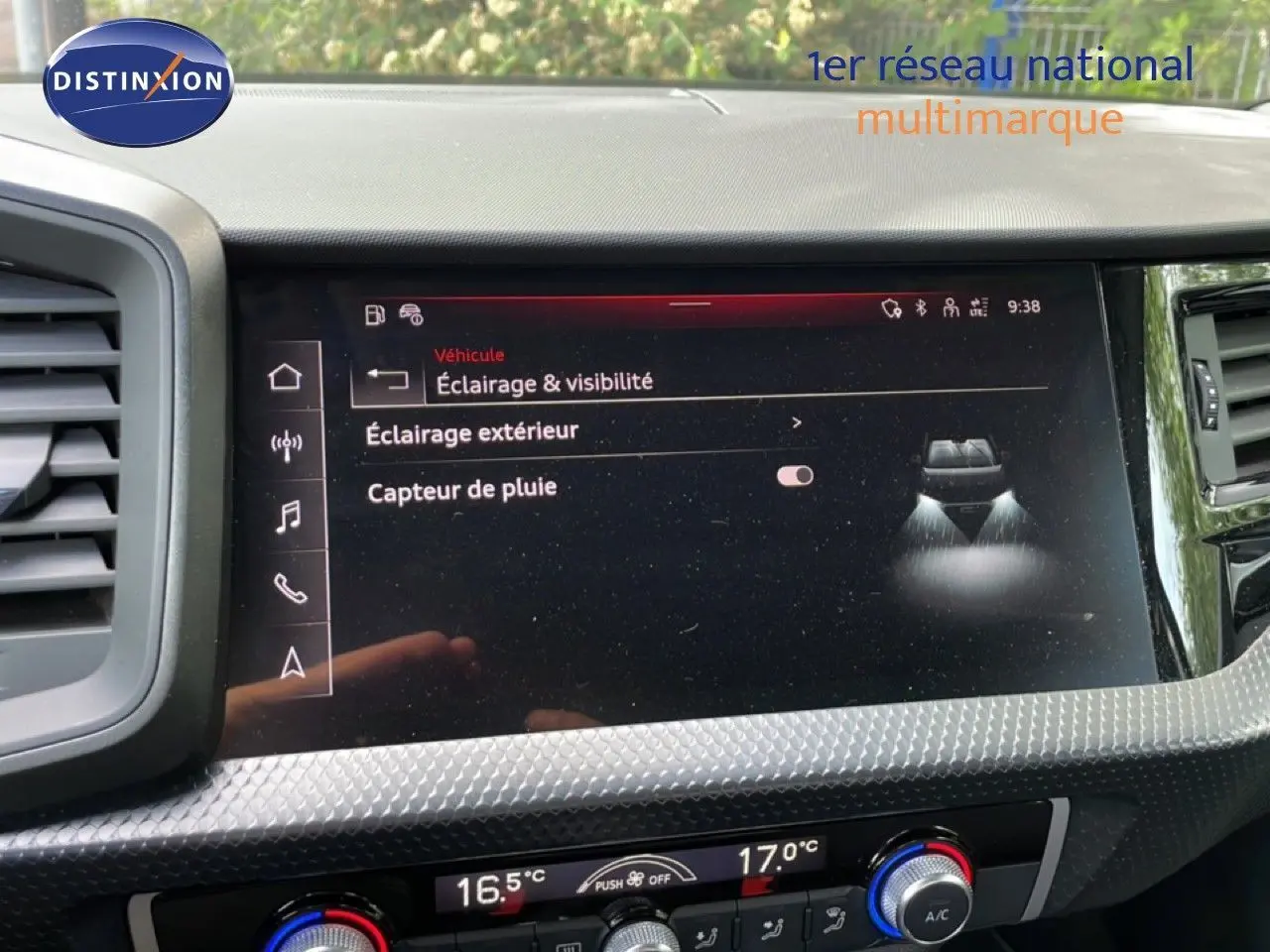 Vue rapprochée de l'écran tactile central de l'Audi A1 Sportback 2023 noir mythe metal, affichant les réglages d'éclairage et capteur de pluie.