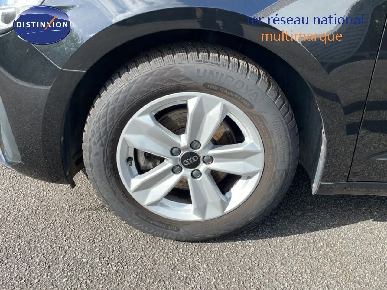 Gros plan sur la roue avant gauche d’une Audi A1 Sportback noire Mythe Metal avec jante argentée cinq branches.
