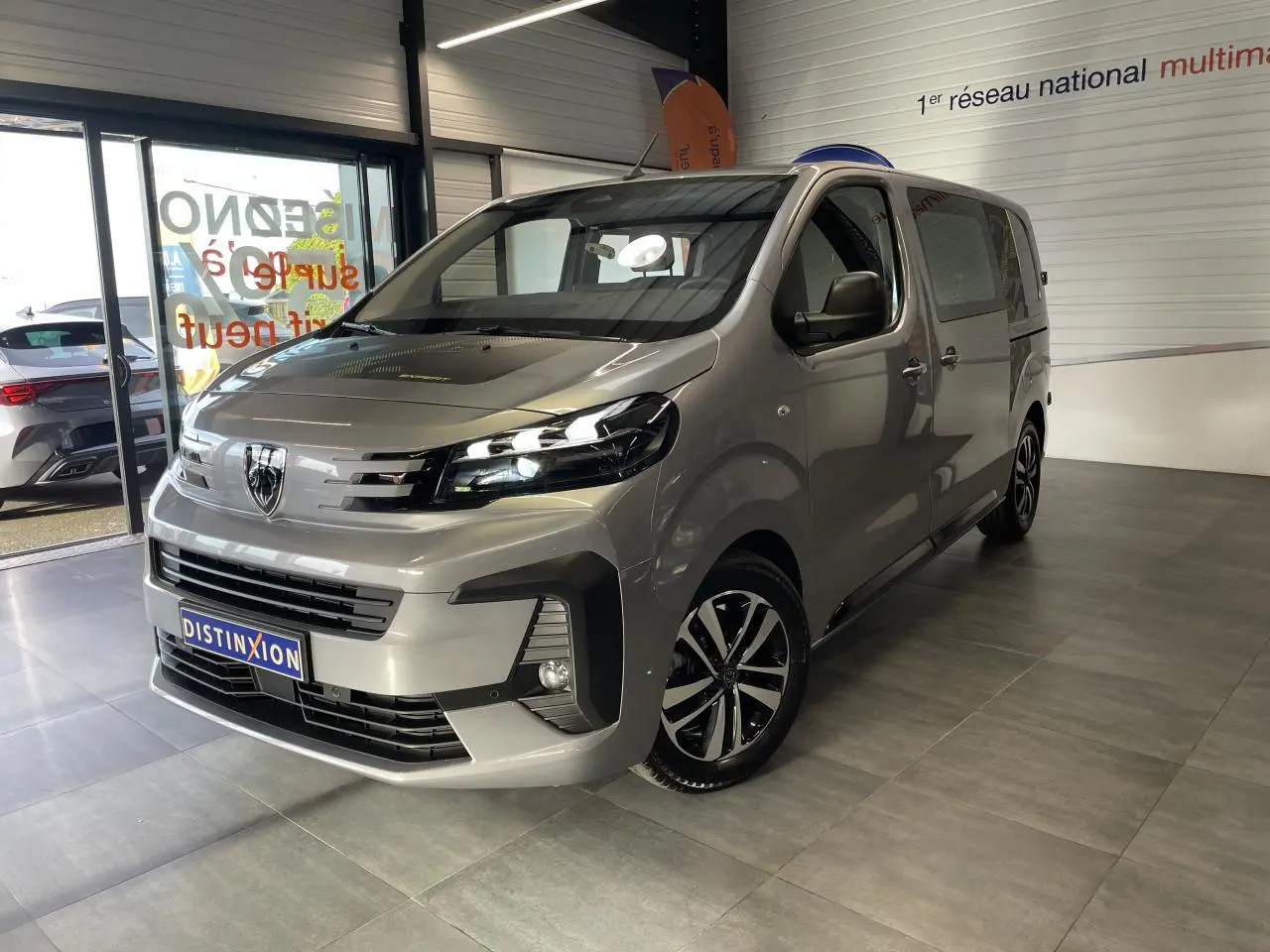 Vue 3/4 avant droit du Peugeot Expert Fourgon gris Artense avec jantes alliage et calandre distinctive en showroom.