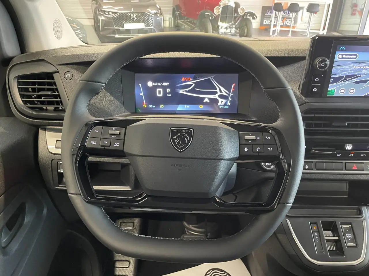 Vue intérieure centrée sur le volant cuir noir et l'écran numérique du tableau de bord du Peugeot Expert Fourgon gris Artense.