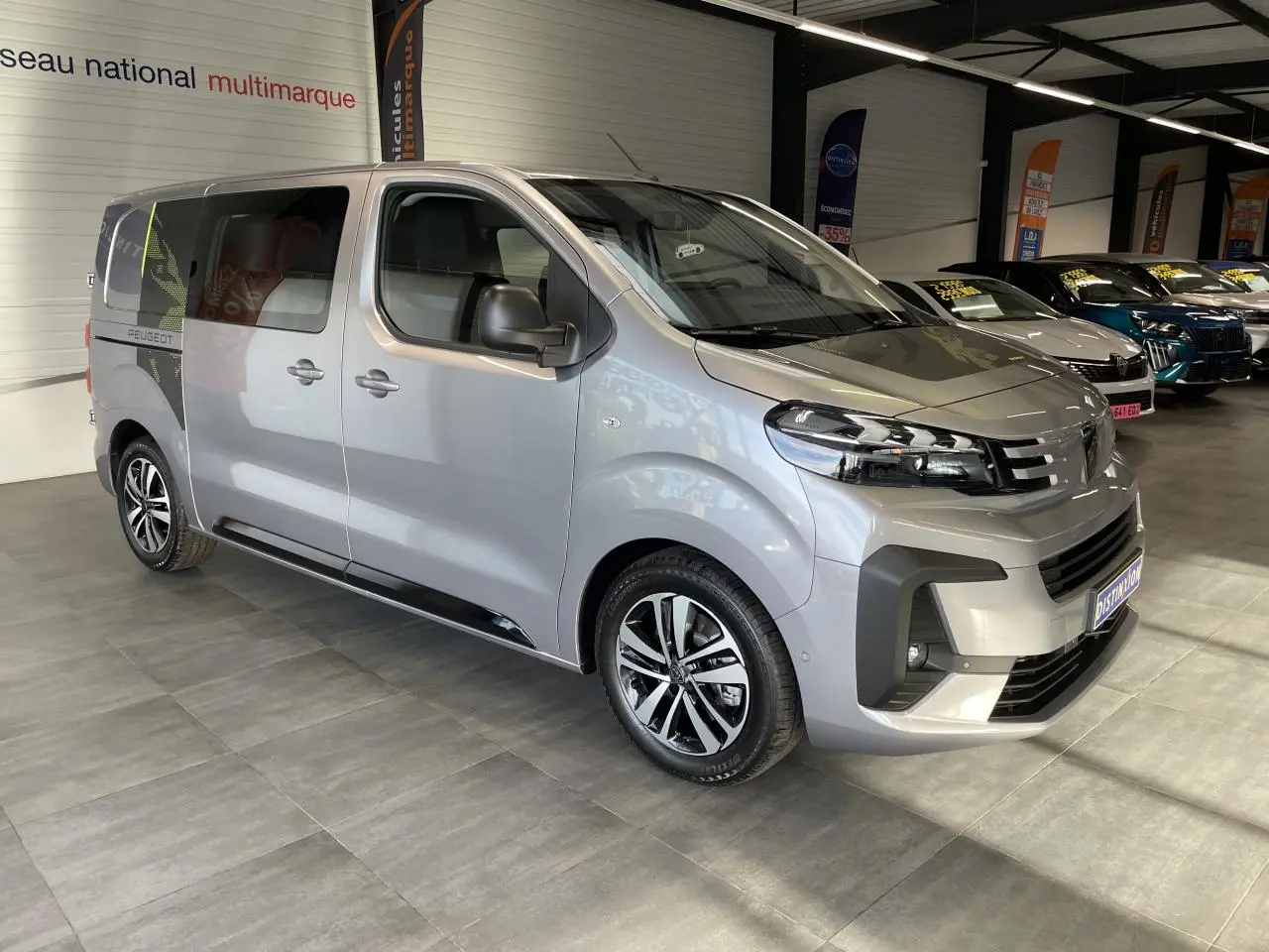 Vue 3/4 avant droit du Peugeot Expert Fourgon gris Artense avec jantes alliage et porte latérale coulissante gauche visible.