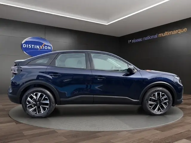Vue latérale droite d'une Citroën C4 hybride 2025 bleu profond avec jantes alliage et toit incliné.