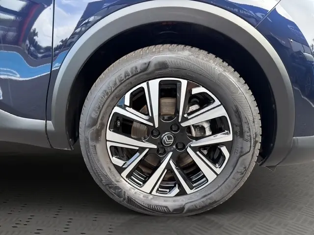 Gros plan sur la jante alliage avant droite noire et argentée du Citroën C4 hybride bleu 2025.