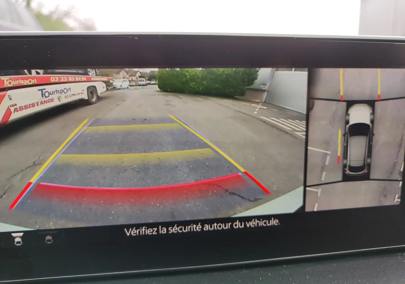 Vue de la caméra de recul et vue aérienne du Mazda MX-30 gris clair en stationnement, avec repères de guidage colorés.