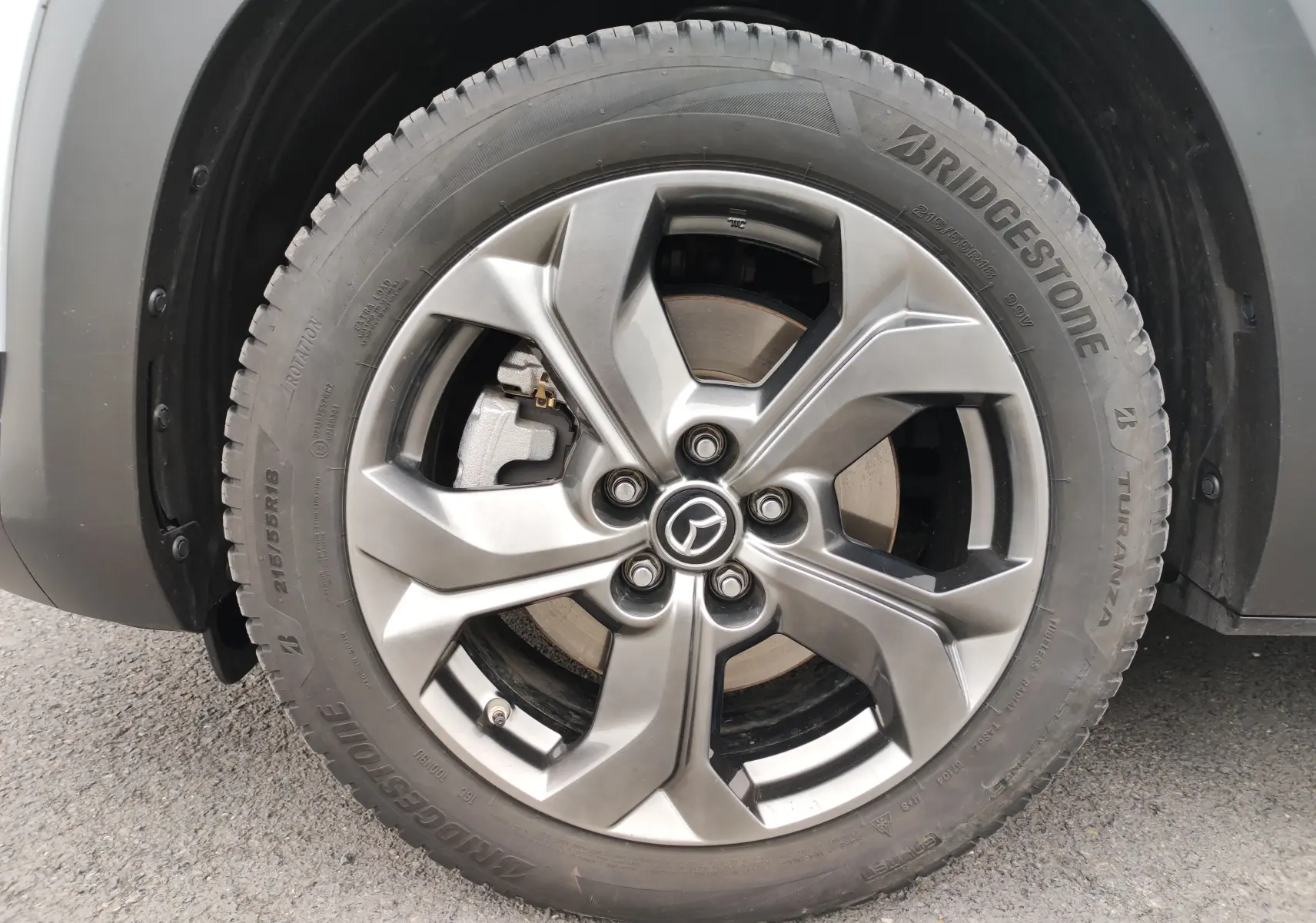 Gros plan sur la roue avant gauche gris clair d’un Mazda MX-30 2023 avec jante alliage et pneu Bridgestone.