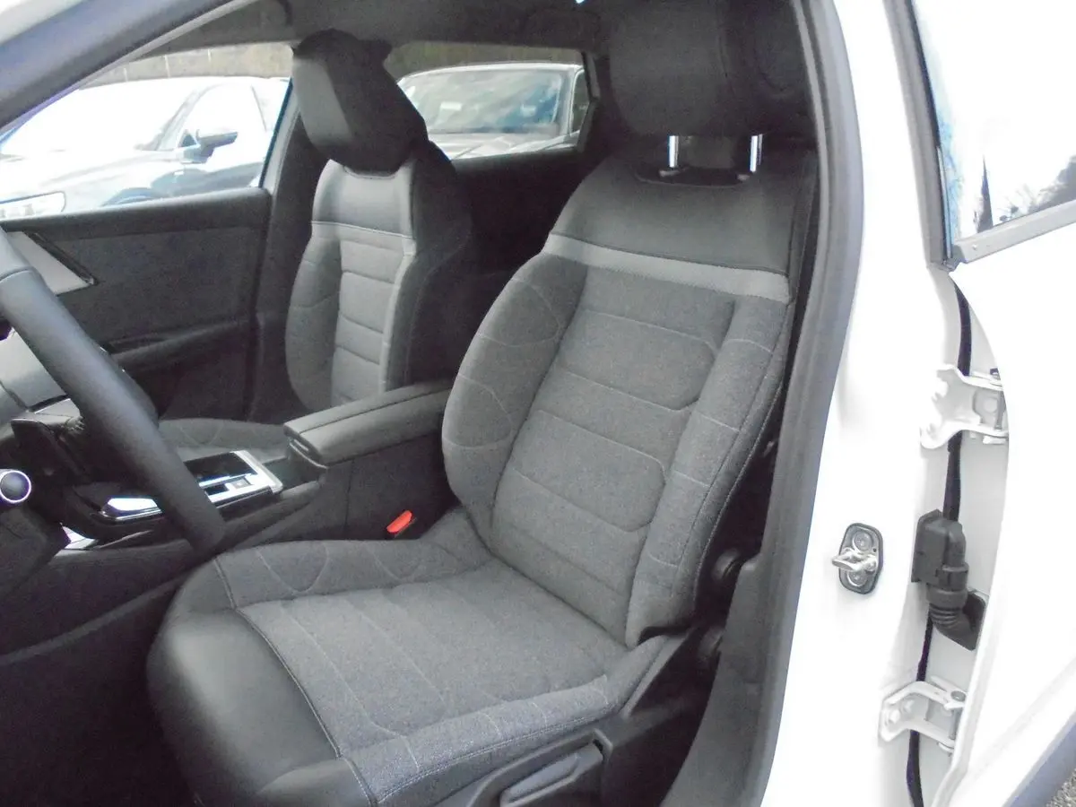 Vue intérieure côté conducteur d'une Citroën C5 X 2022 blanc nacré, siège avant en tissu gris avec appuie-tête intégré.