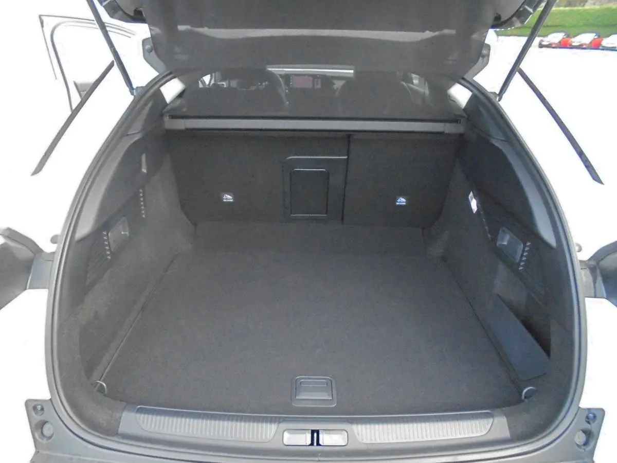 Coffre ouvert vu de l'arrière d'une Citroën C5 X blanc nacré, montrant un espace de chargement spacieux et propre.