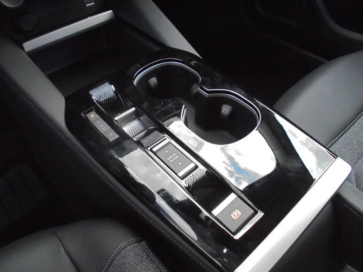 Gros plan sur la console centrale noire brillante de la Citroën C5 X 2022 avec commandes de boîte auto et porte-gobelets.