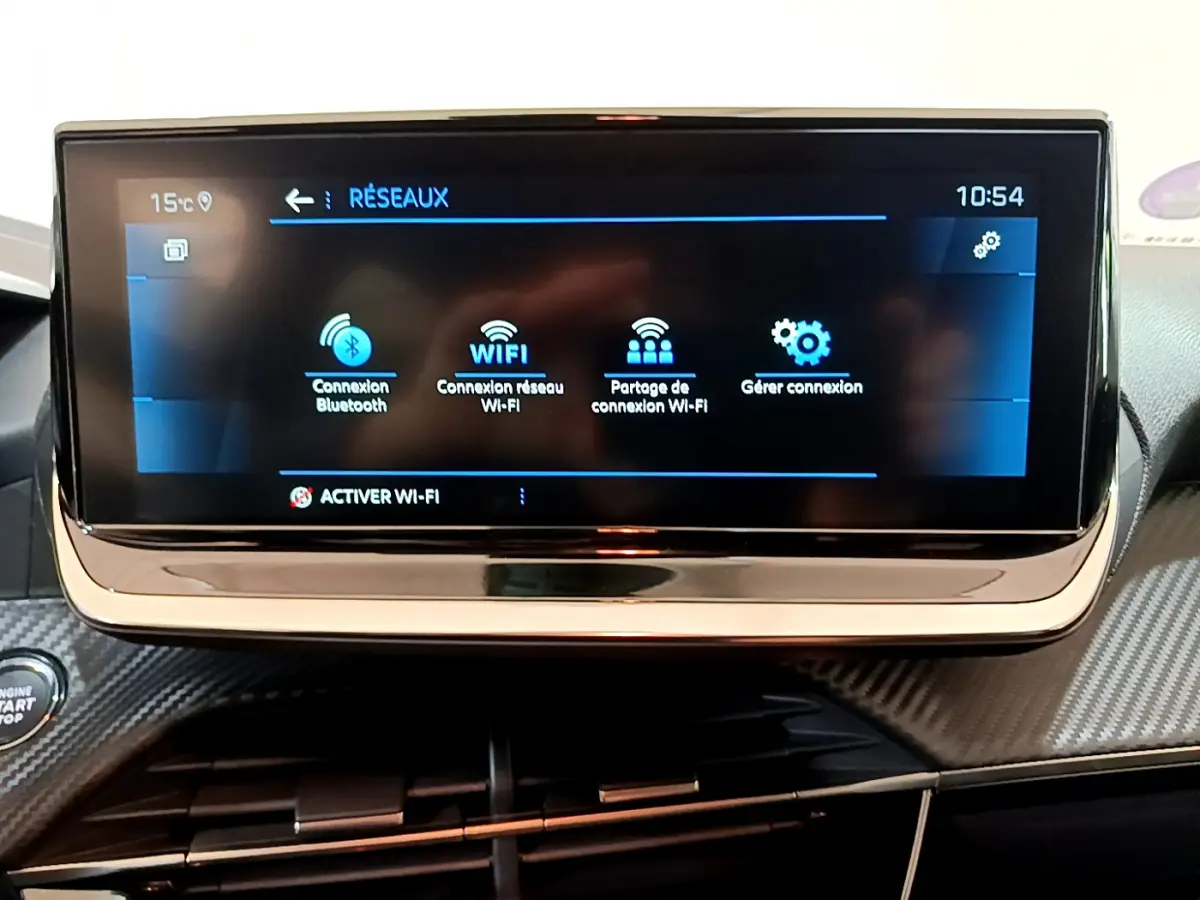 Écran tactile central de la Peugeot 208 gris foncé, affichant les options de connexion Bluetooth et Wi-Fi.