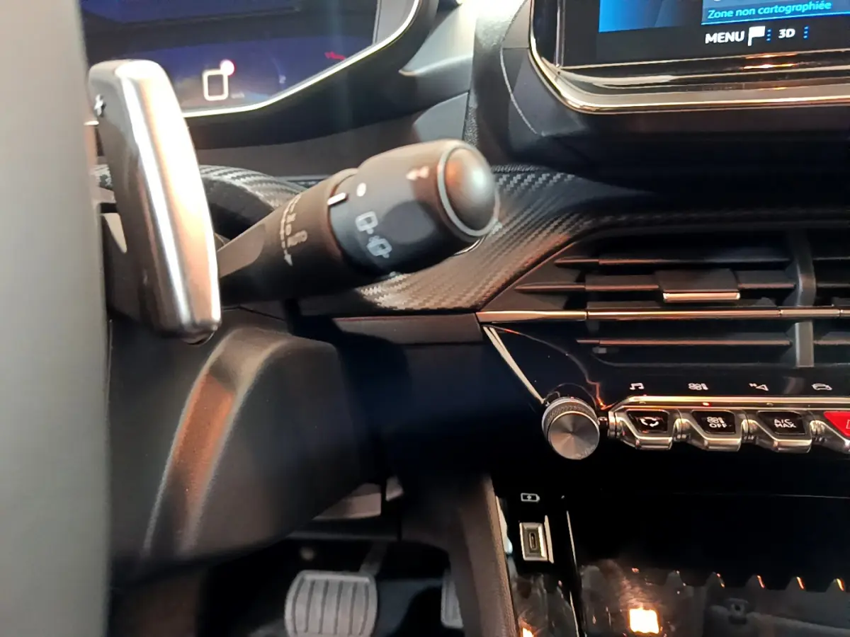 Détail intérieur côté gauche du tableau de bord et commandes de la Peugeot 208 gris foncé 2022 PureTech Allure Pack.