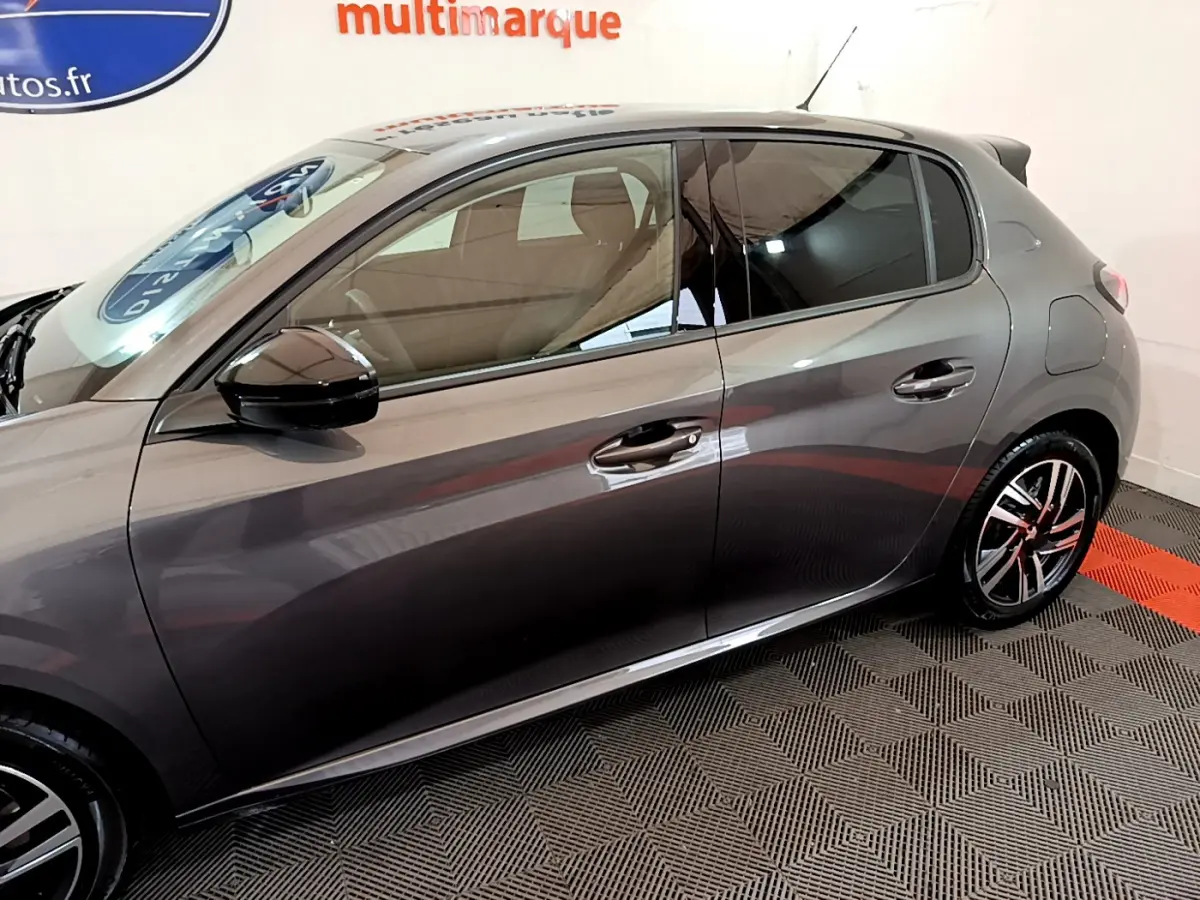 Vue latérale droite d'une Peugeot 208 gris foncé, mettant en valeur les jantes alliage et les rétroviseurs noirs brillants.