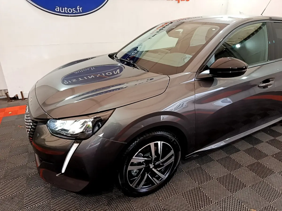 Peugeot 208 gris foncé vue en 3/4 avant droit, mettant en valeur ses phares LED et jantes alliage distinctives.