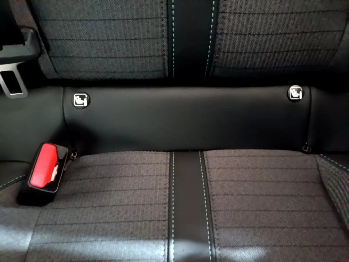 Vue rapprochée de la banquette arrière gris foncé de la Peugeot 208 avec coutures bleues et ancrages Isofix visibles.
