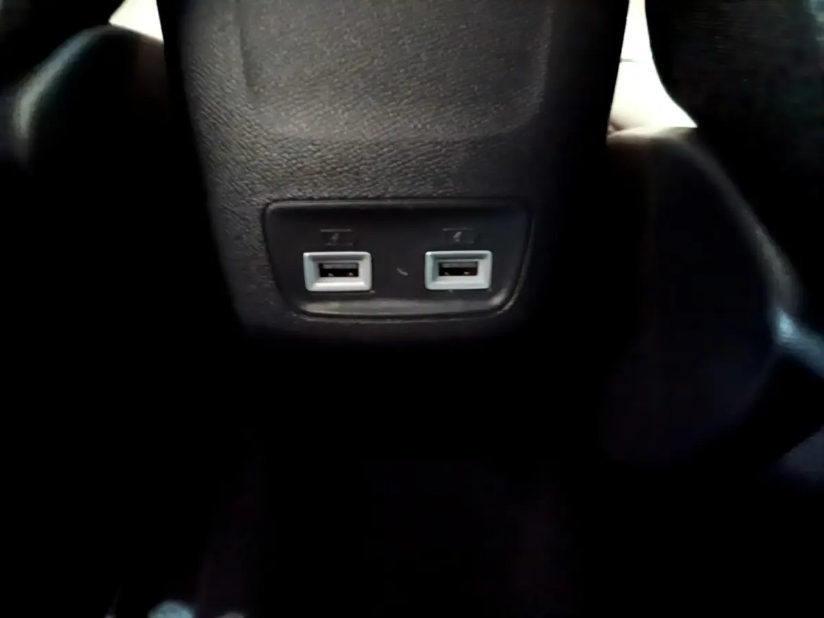 Gros plan sur les deux ports USB arrière intégrés dans le console centrale noire du Peugeot 208 gris foncé.
