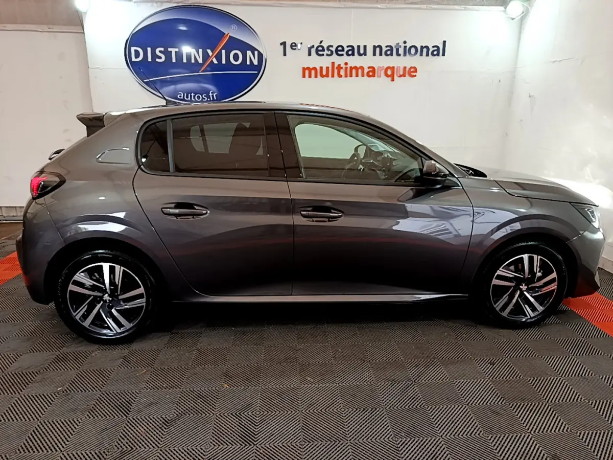 Peugeot 208 gris foncé vue de profil côté gauche, avec jantes alliage et vitres teintées en intérieur showroom.