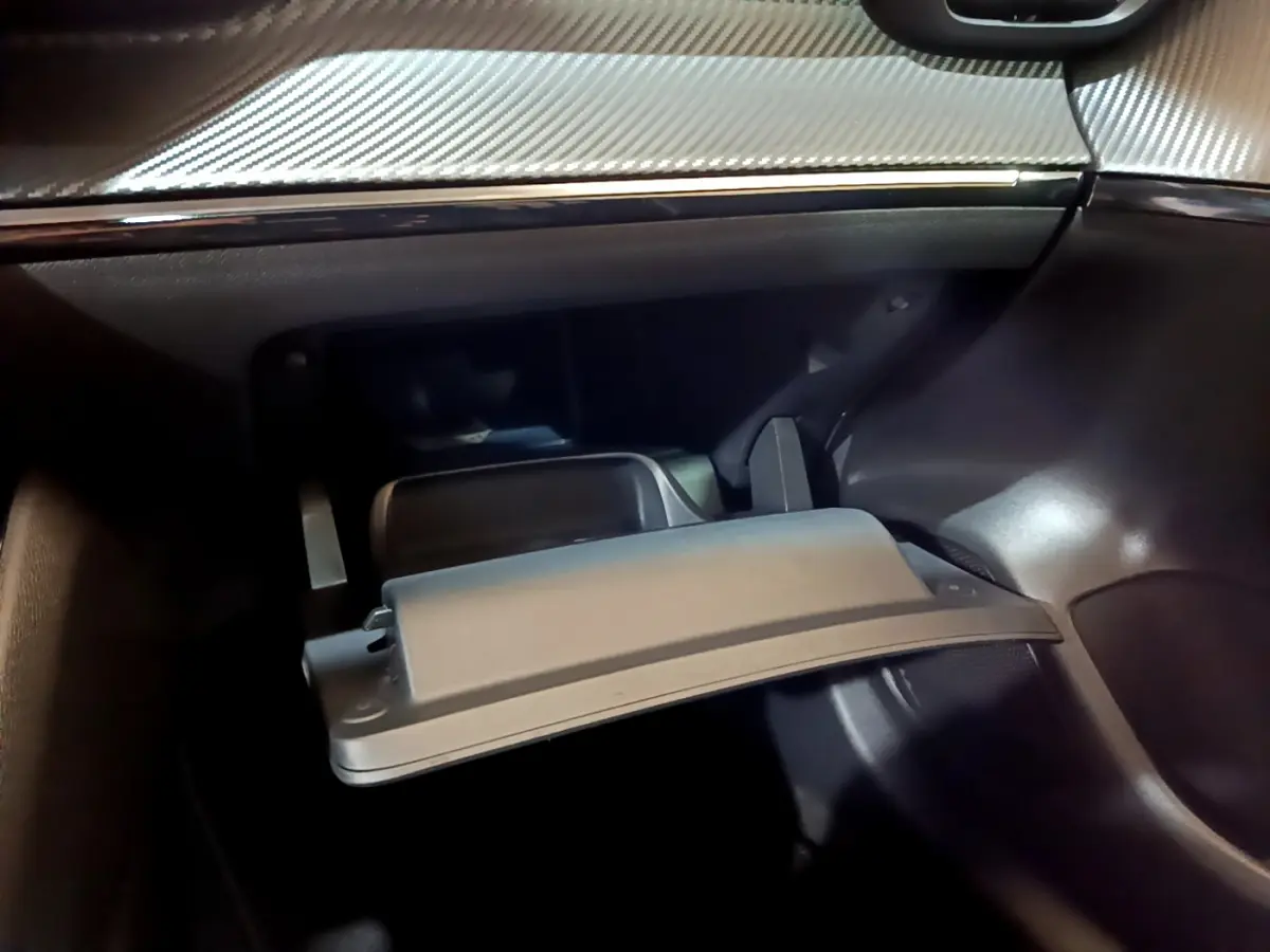 Vue rapprochée de la boîte à gants ouverte dans l’habitacle gris foncé de la Peugeot 208 PureTech 2022.